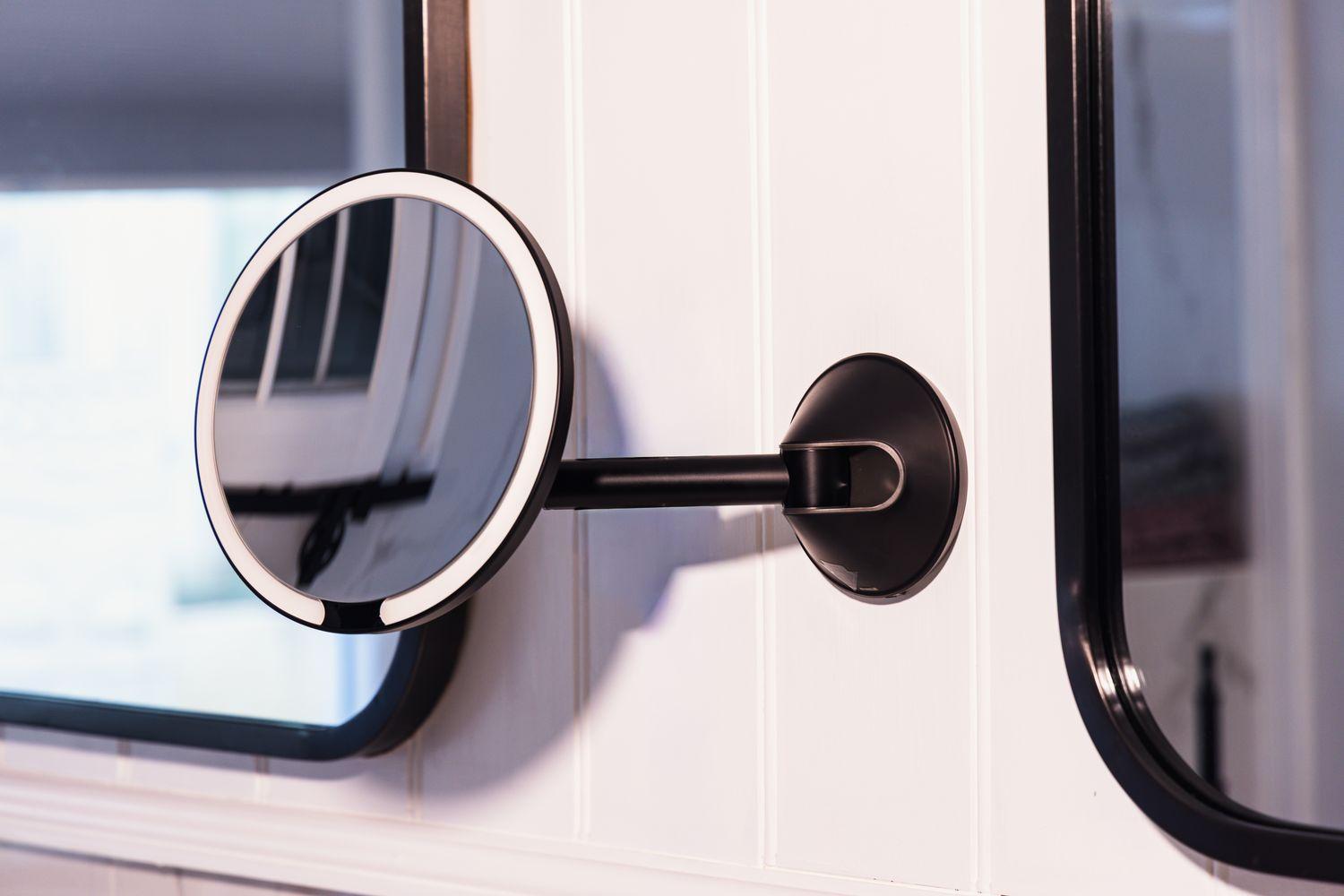 A wall mounted makeup mirror above a bathroom vanity